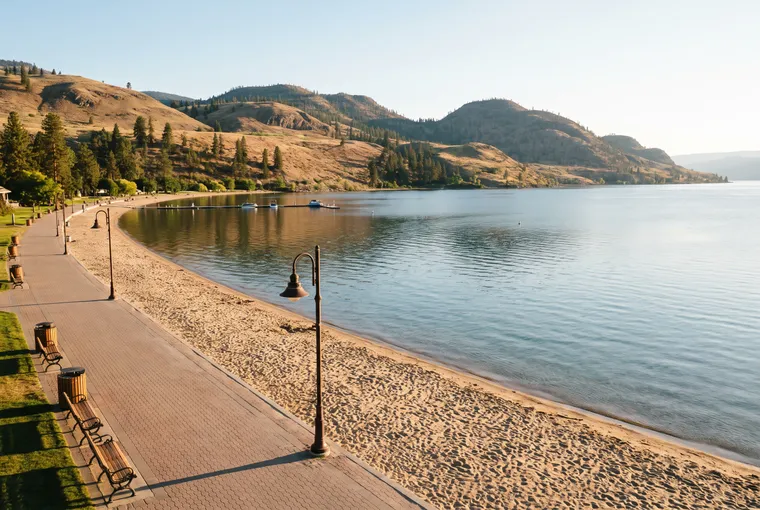 Illustration: a paved lakeside promenade with lamp posts and benches beside a sandy beach and calm lake, dry hills on the far shore.